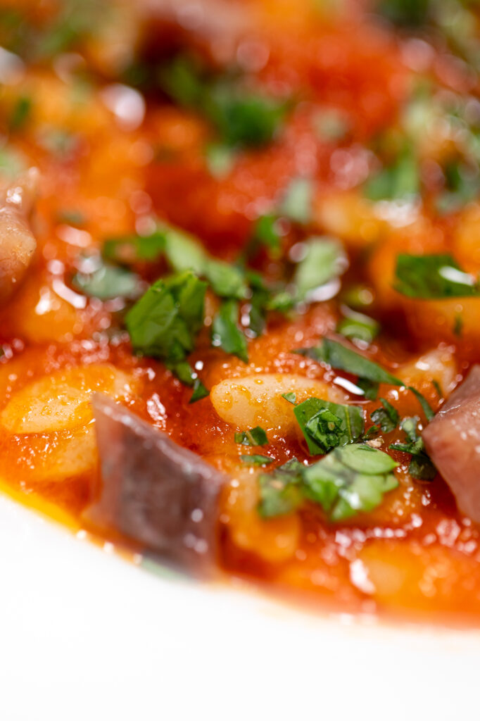 Dettaglio di un piatto con Chicchi di grano Mancini, salsa di pomodoro, prezzemolo e alici