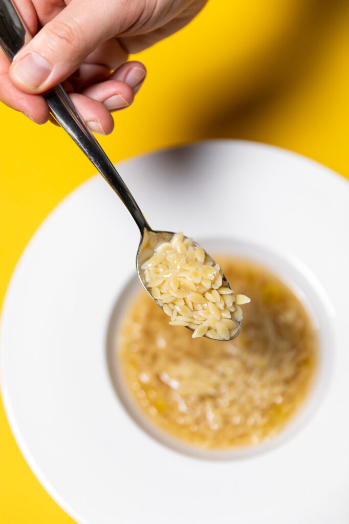Dettaglio di un piatto e di un cucchiaio  con Chicchi di grano Mancini in brodo vegetale